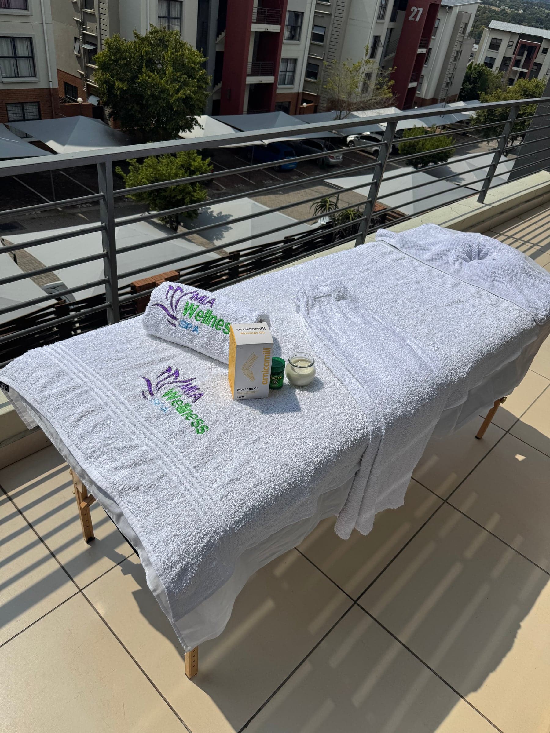 Prepared massage table on a balcony with Mia Wellness Spa towels and treatment essentials ready for a house-call appointment.