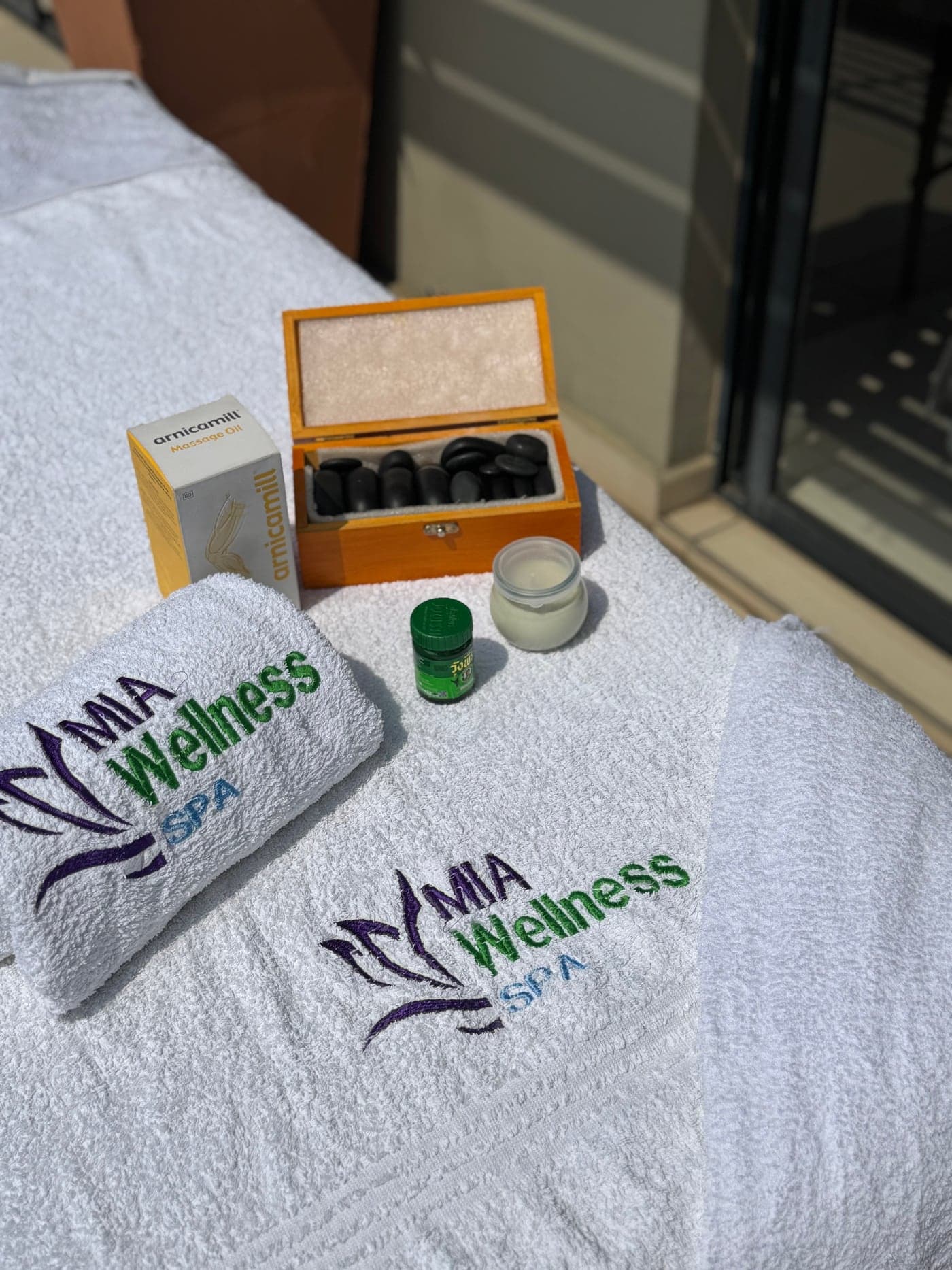 Close-up of Mia Wellness Spa towels, massage products, and hot stone tools arranged on a prepared treatment table.